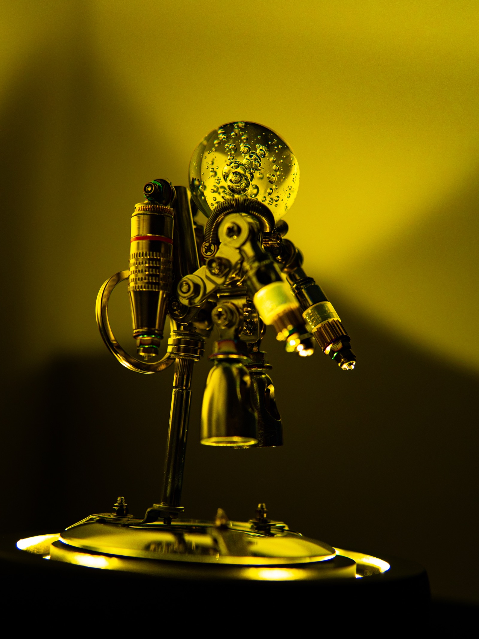 Close detail of the Nebula Astronaut's mechanical backpack and glass dome head under yellow light