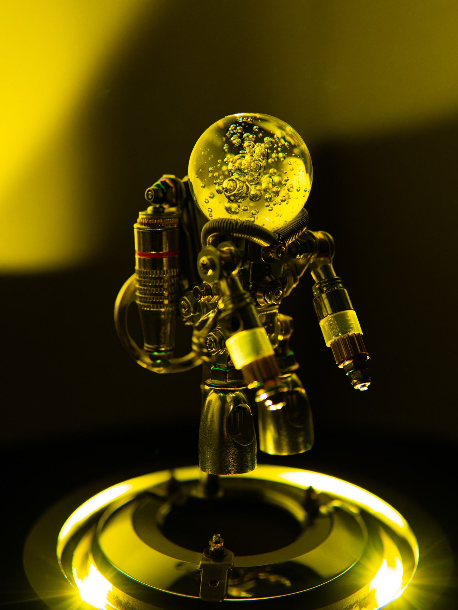Front view of the finished Nebula Astronaut figure glowing under warm light, showing the mechanical arms and glass dome head